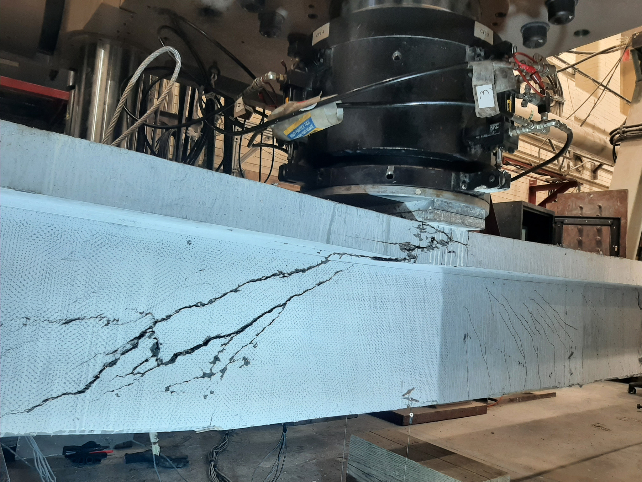 Shear cracking in a full-scale UHPC girder beneath a loading actuator